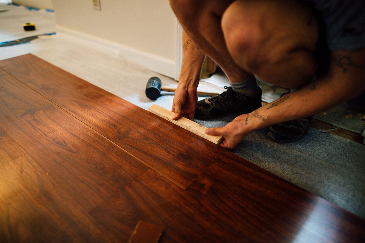 Installer tapping laminate plank flooring into place with a mallet