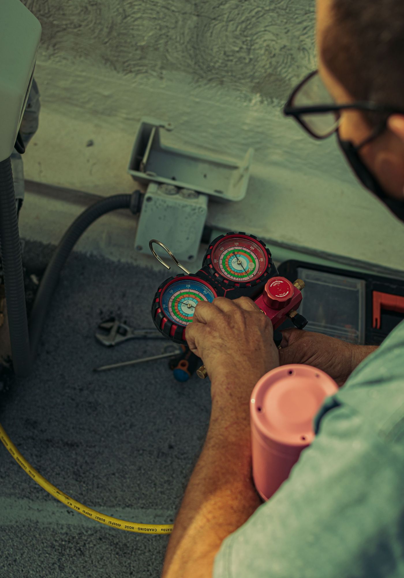 Hands adjusting a refrigerant manifold gauge during an AC service