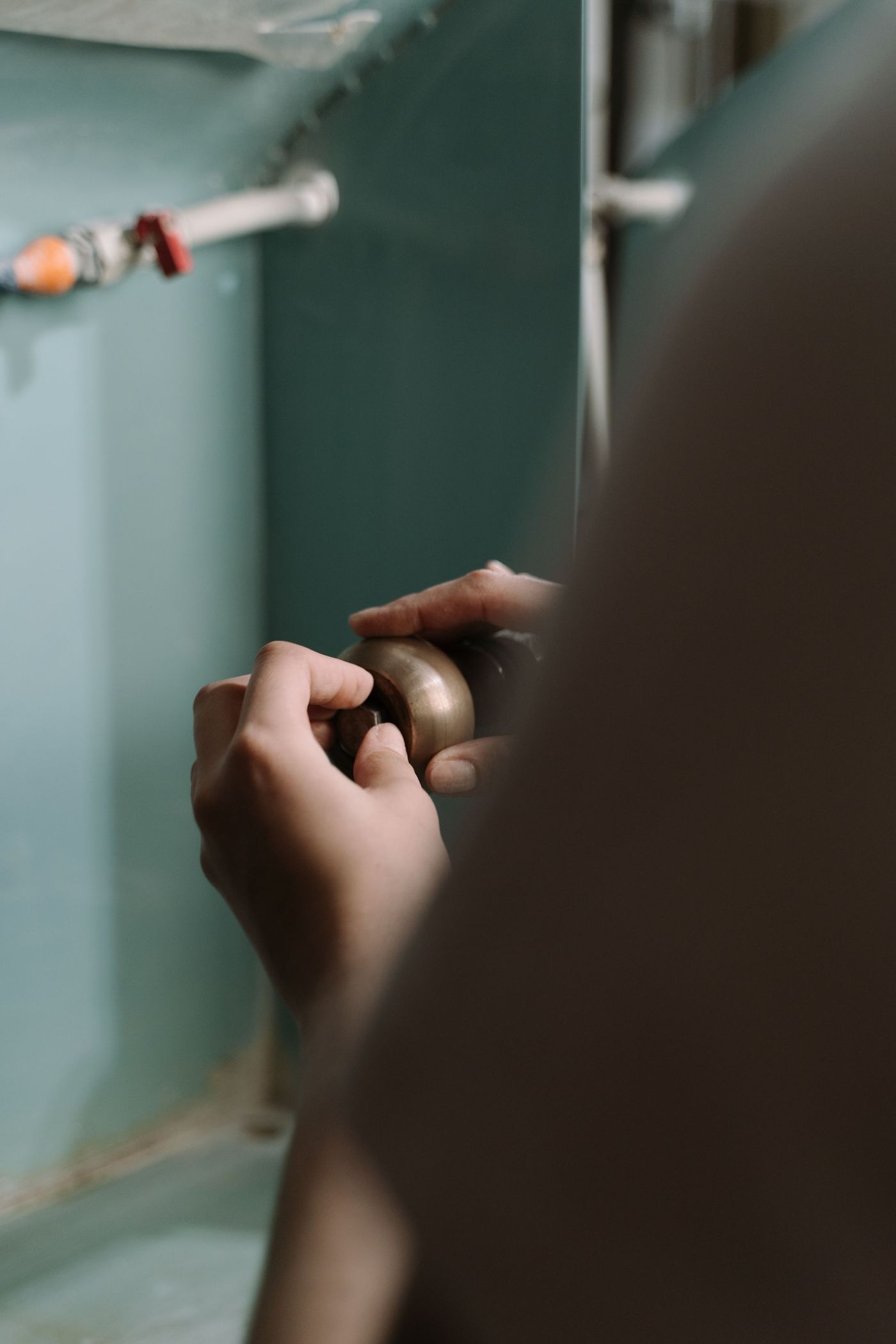 Hands adjusting the drain pipe under a kitchen sink