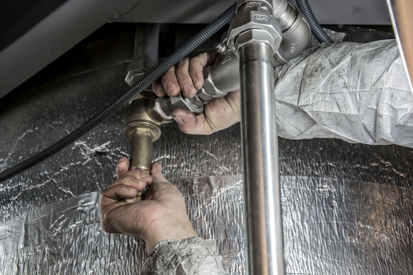 Plumber hands fitting steel pipe sections together indoors