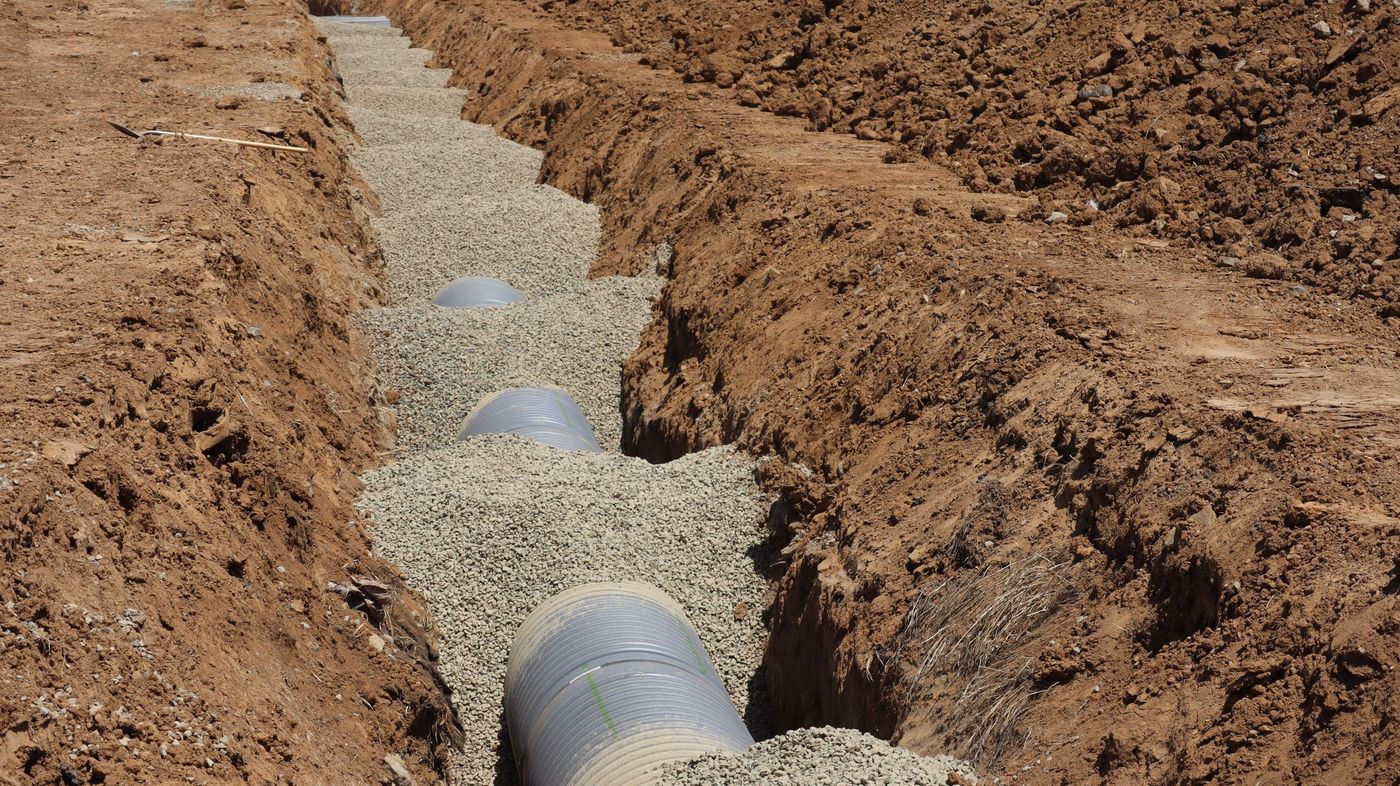 Drainage pipe being installed in a freshly dug trench